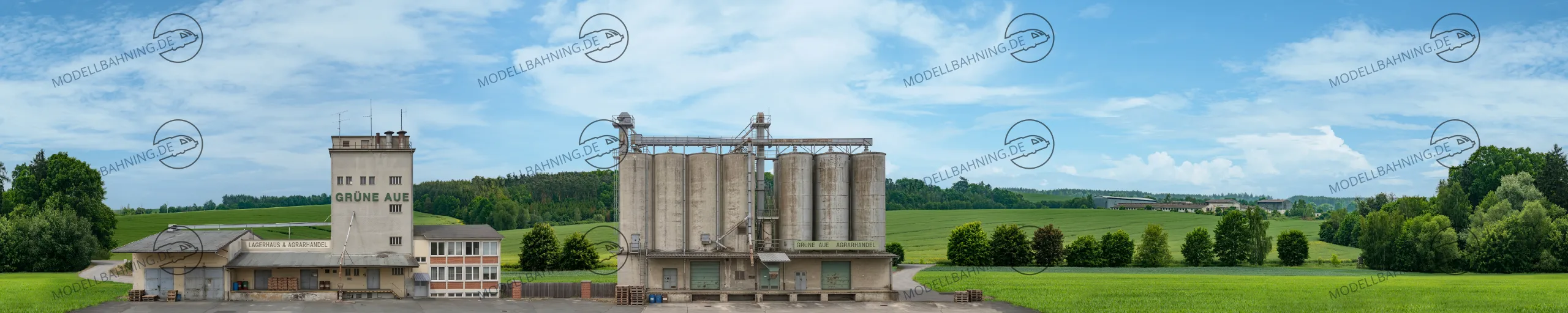 Spur 0 1970er Jahre Modellbahnhintergrund – Grüne Aue zeigt den einen typischen Agrarhandel mit Silos und Lager inmitten von satten Wiesen und Feldern
